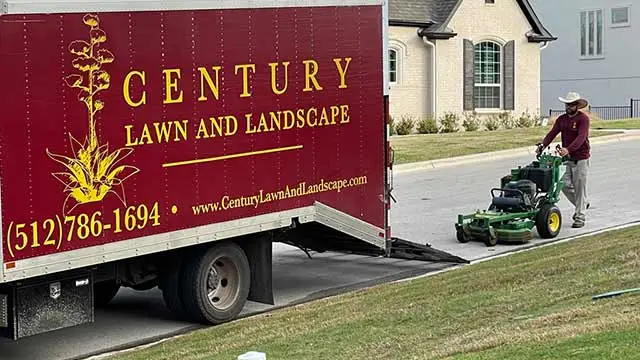 Lawn mowing technician unloading a mower near Austin, TX.