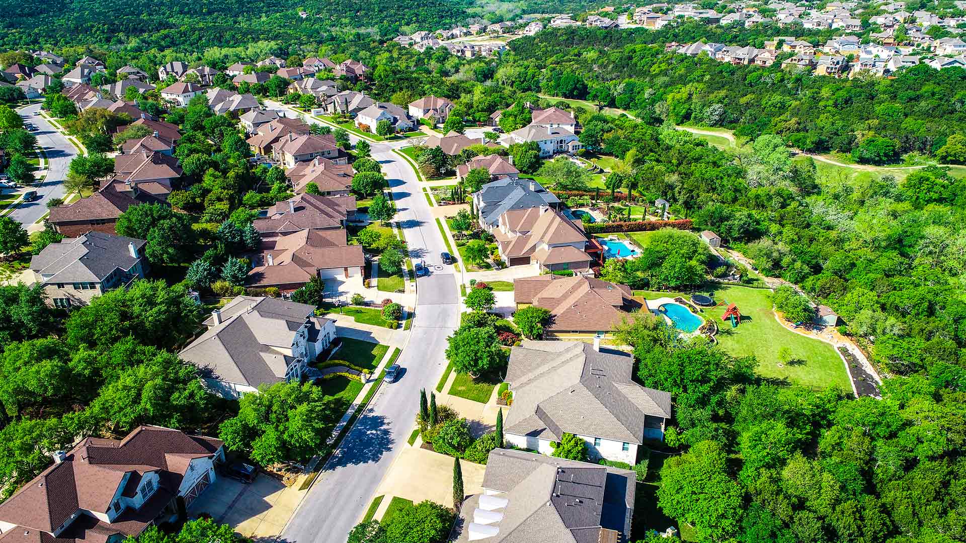 Aerial photo of Cedar Park, TX suburbs amongst hills and green trees.