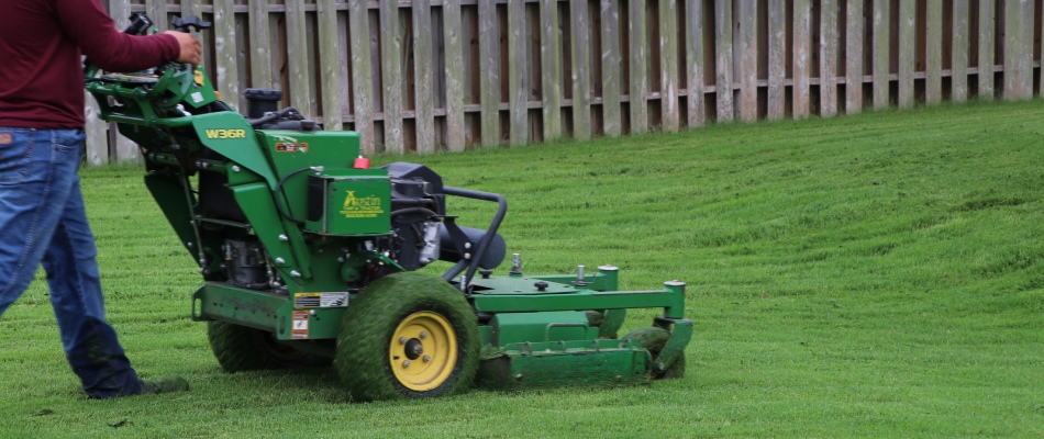 Century worker with green mower in lawn in West Lake Hills, TX.