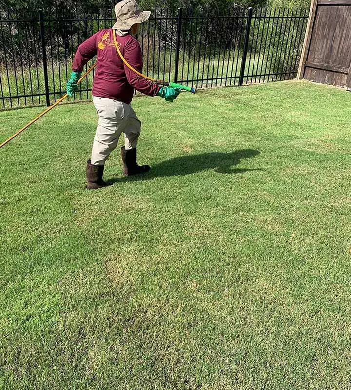 Lawn care worker spraying fertilizer on grass in Austin, TX.